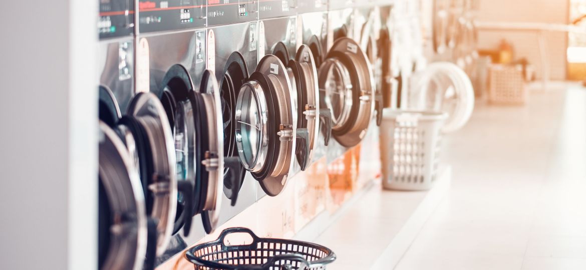 Row of industrial laundry machines in laundromat  in a public laundromat, with laundry in a basket , .Thailand